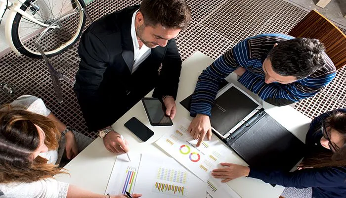 Project managers reviewing plans around a table