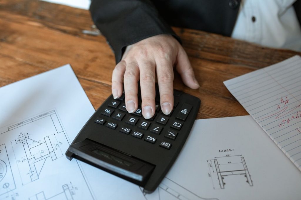 Cost engineer calculating project costs over drawings